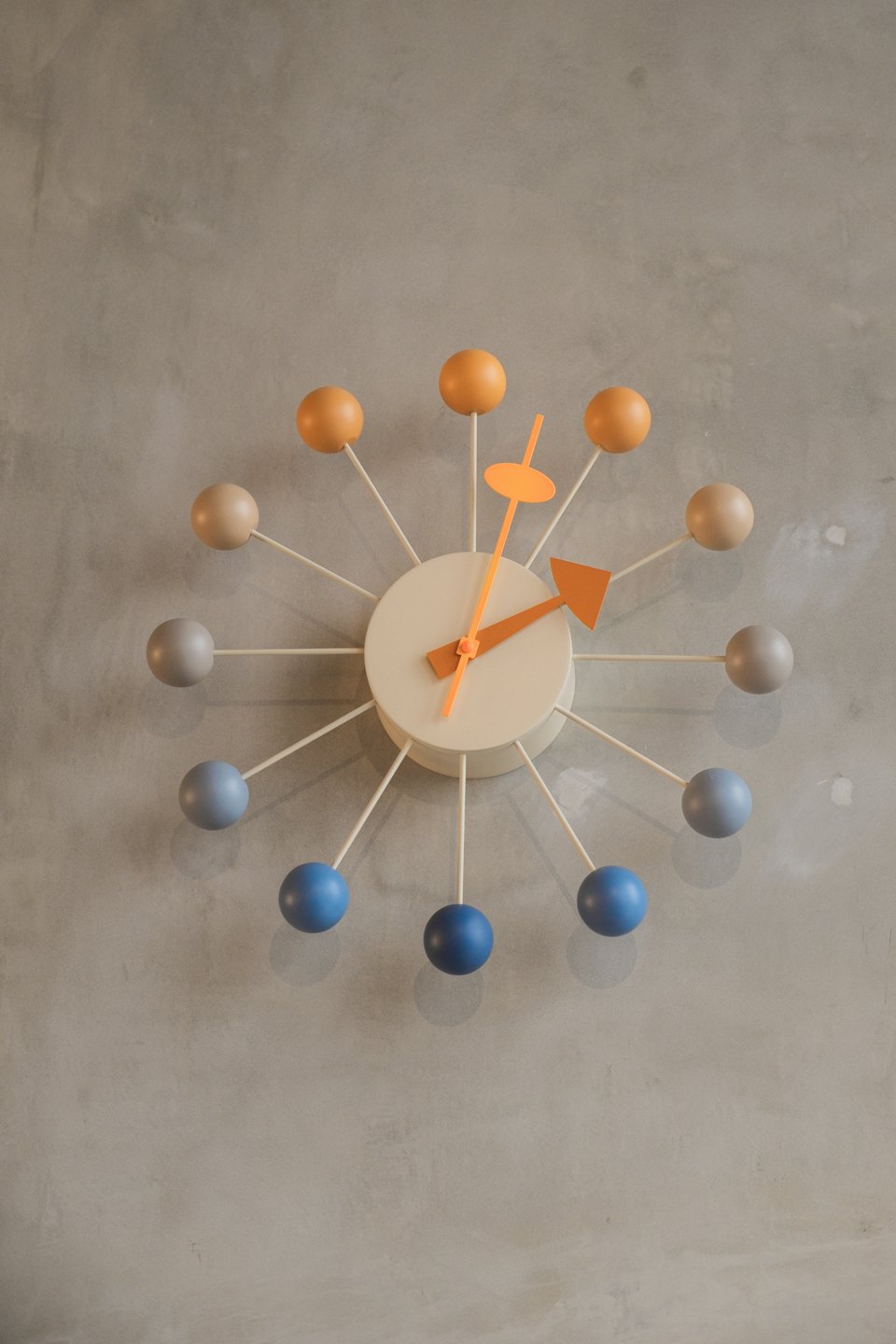 Reloj de pared estilo mid-century colgado en una pared de hormigón.