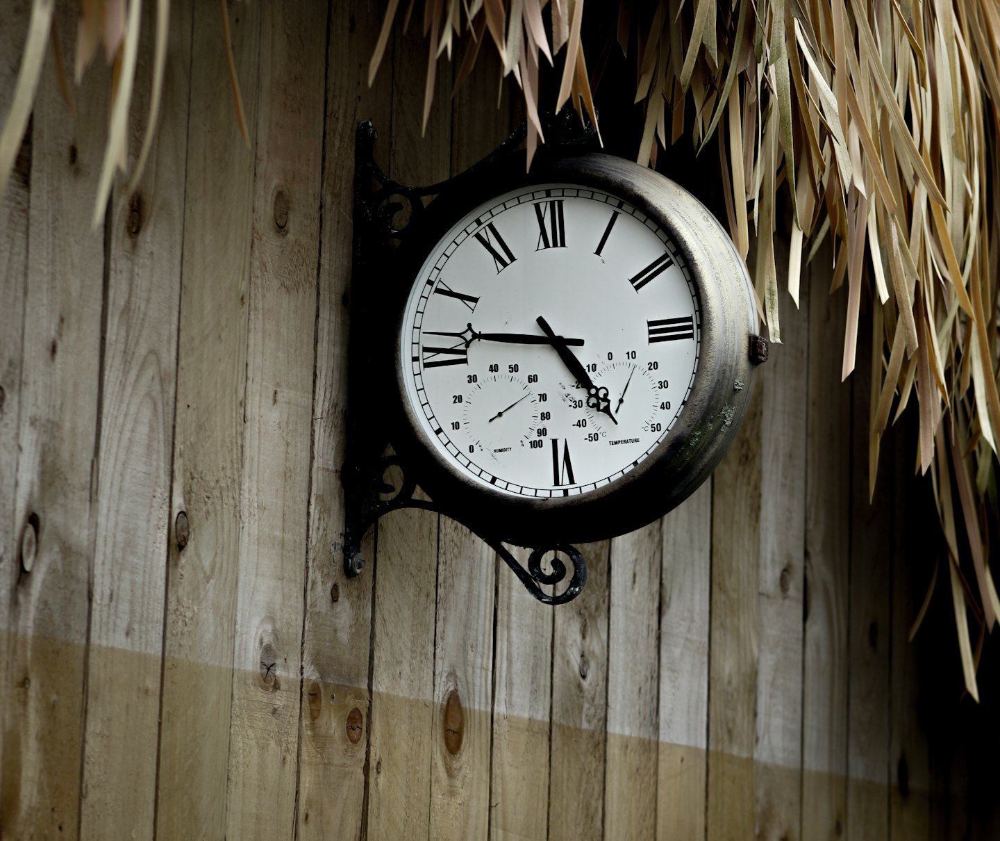 Reloj de pared antiguo montado en una valla de madera rústica.