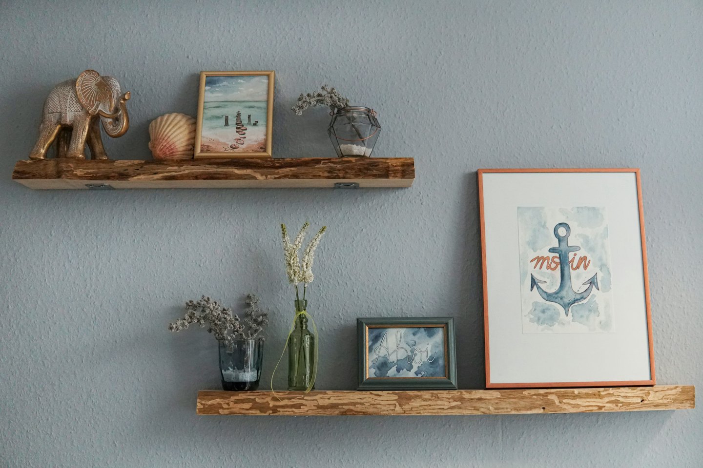 Dos estantes rústicos de madera con decoración sobre una pared gris.