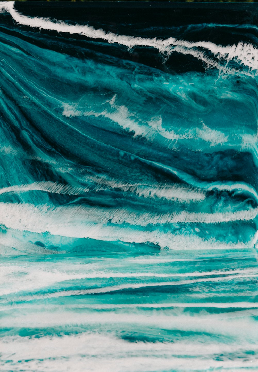 Remolinos abstractos de color verde azulado, azul y blanco que se asemejan a las olas del océano.
