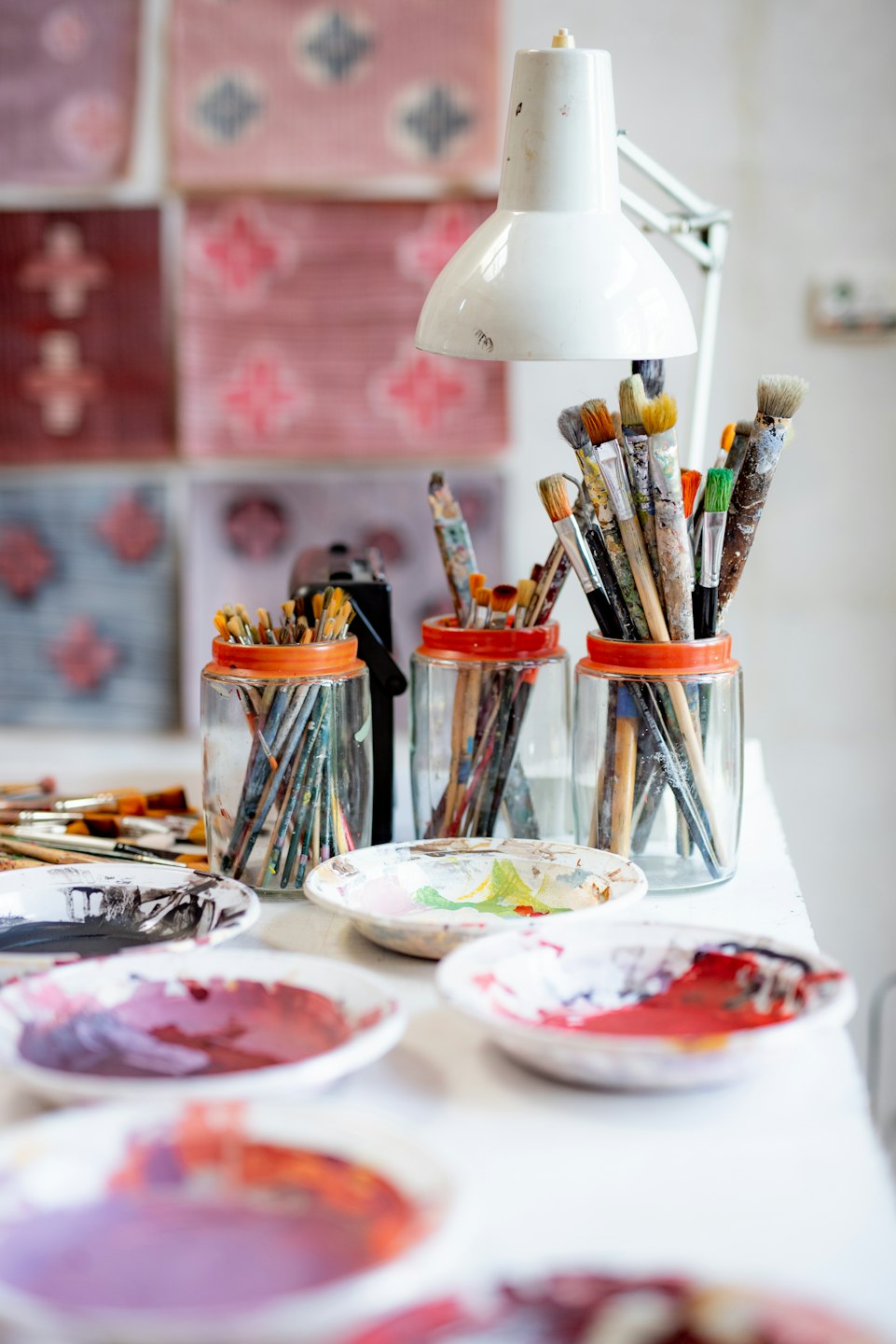 Banco de trabajo de artista con pinceles en tarros y paletas de pintura mezclada.
