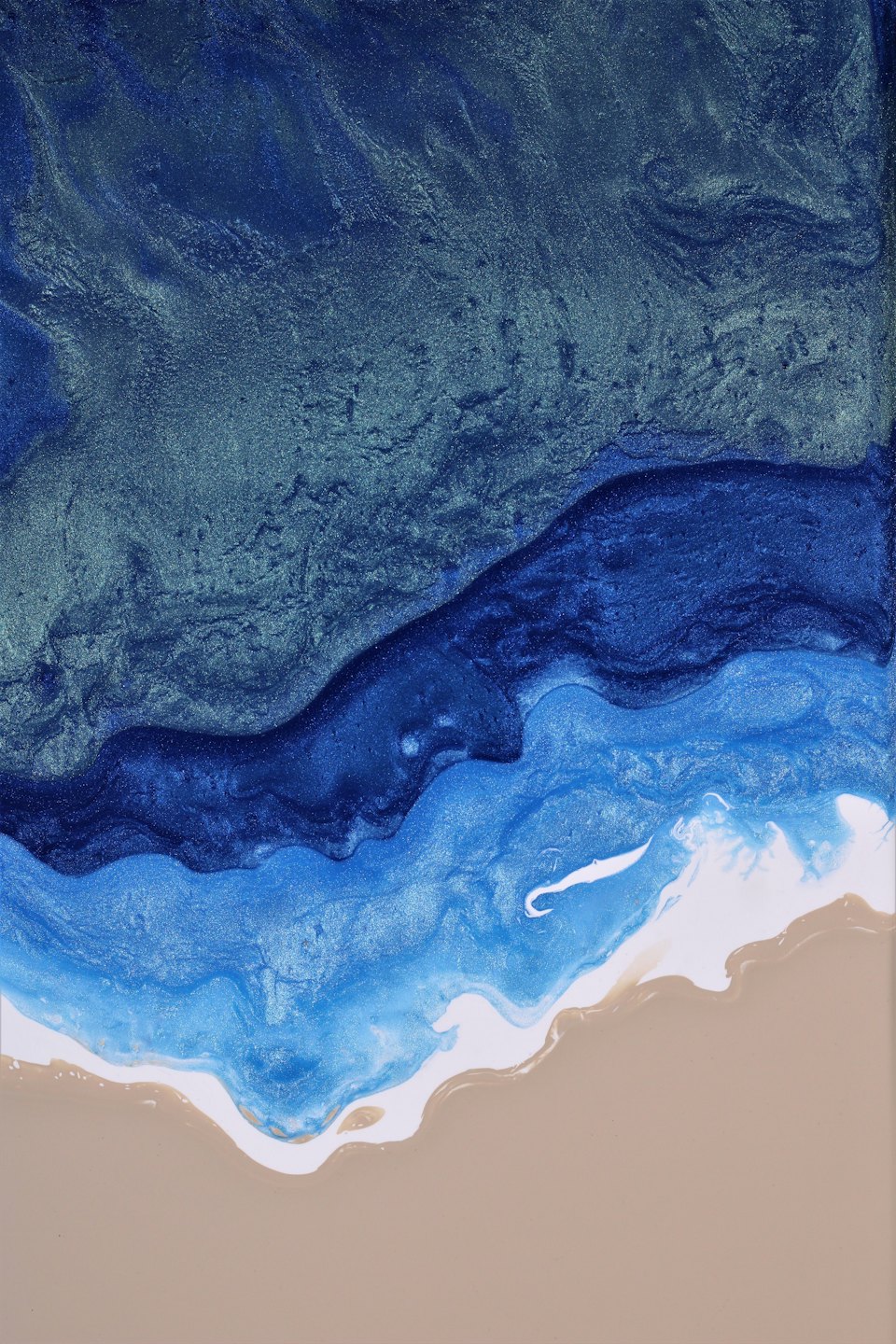 Arte de resina epoxi que representa olas del océano rompiendo en una playa de arena.