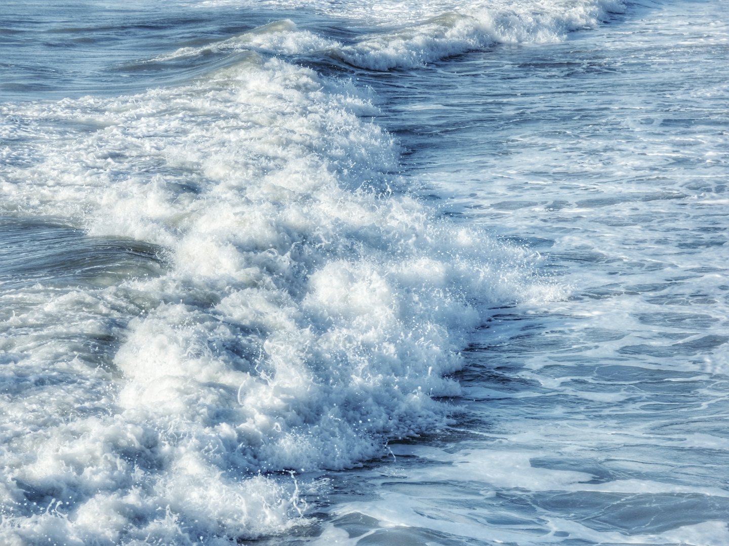 Olas espumosas del océano rompiendo en un día soleado.